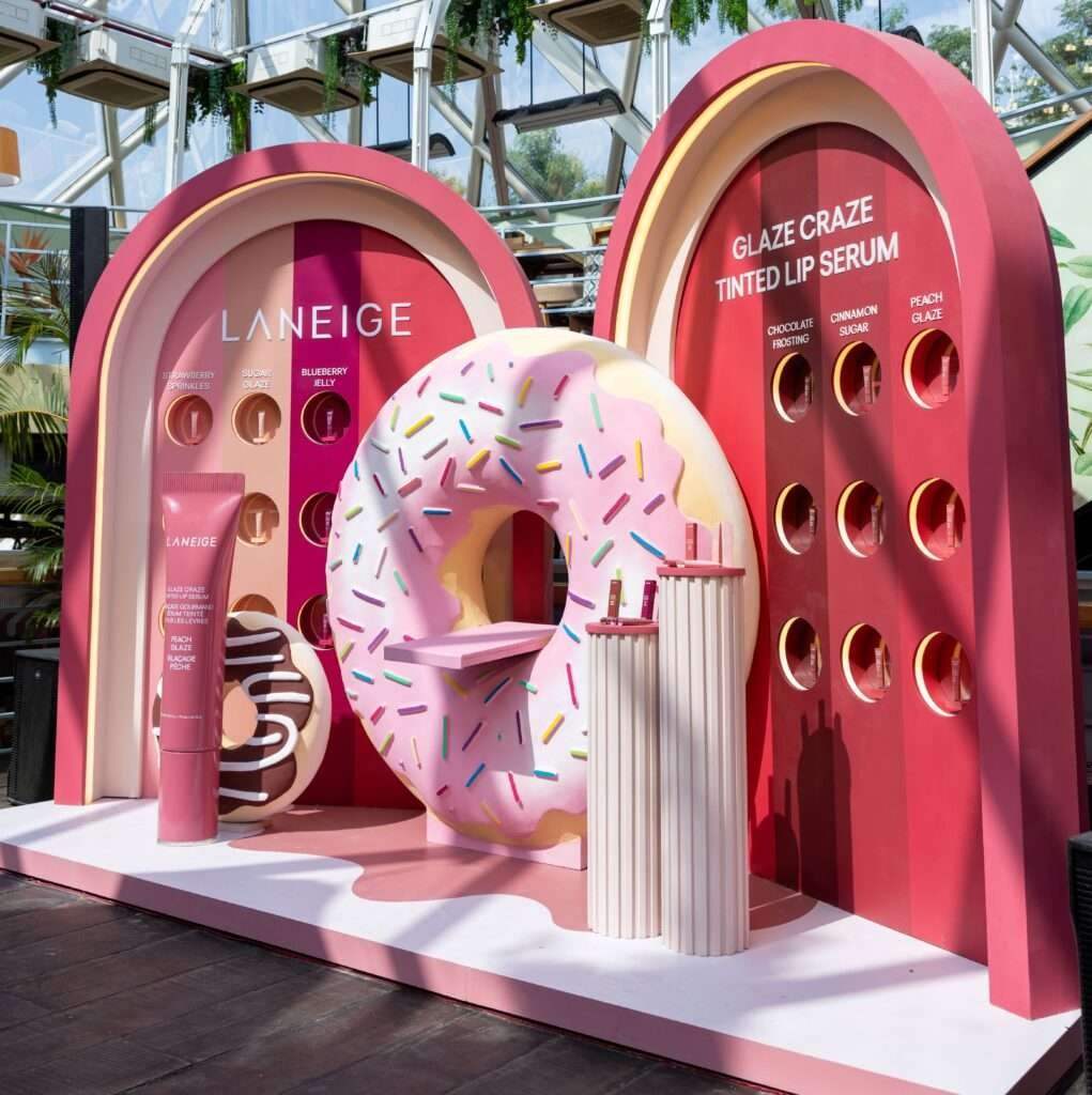 Laneige Glaze Craze Lip Serum promotional display with giant donut and flavor showcase